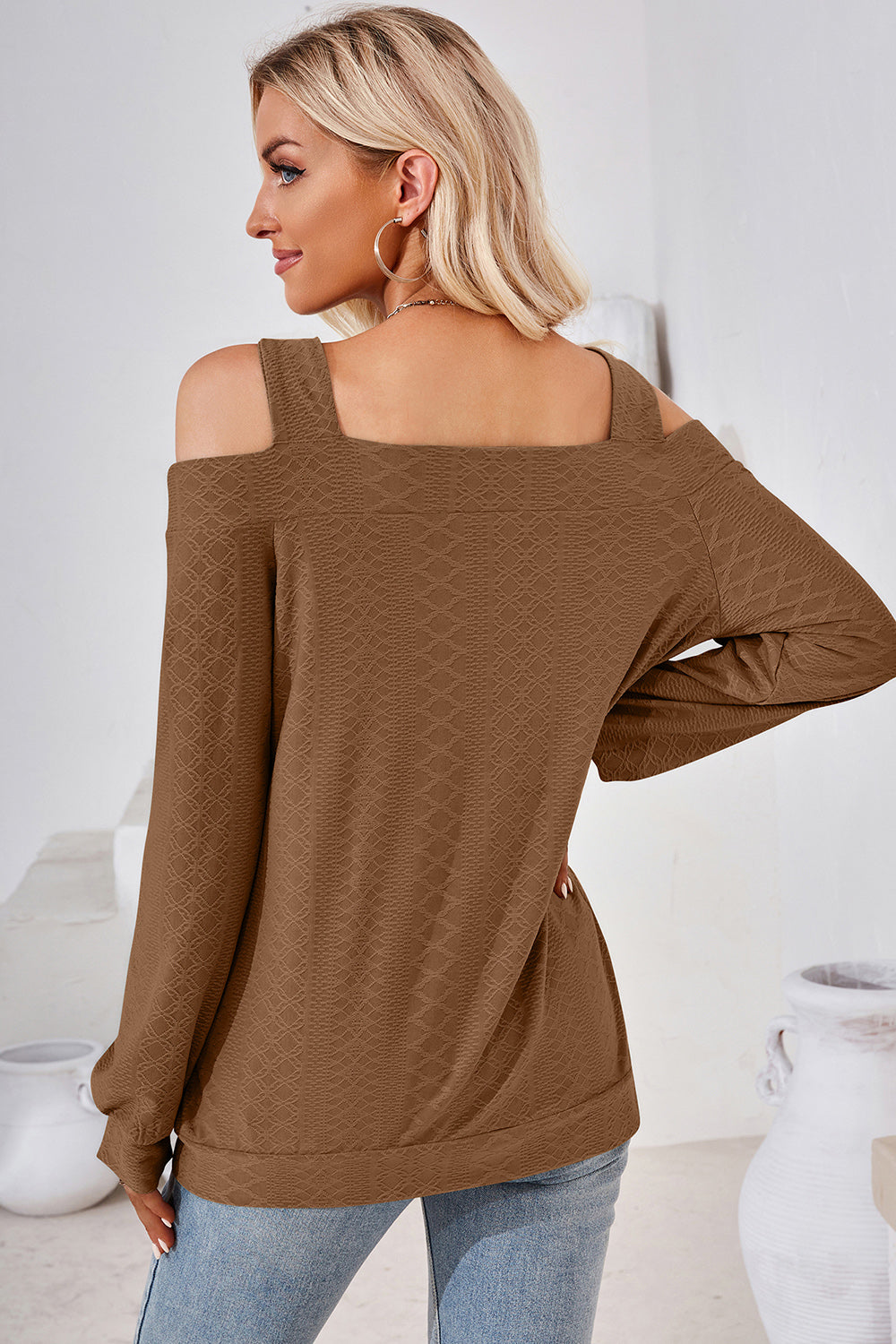 Brown geometric cutout shoulder top with long sleeves and a textured pattern.