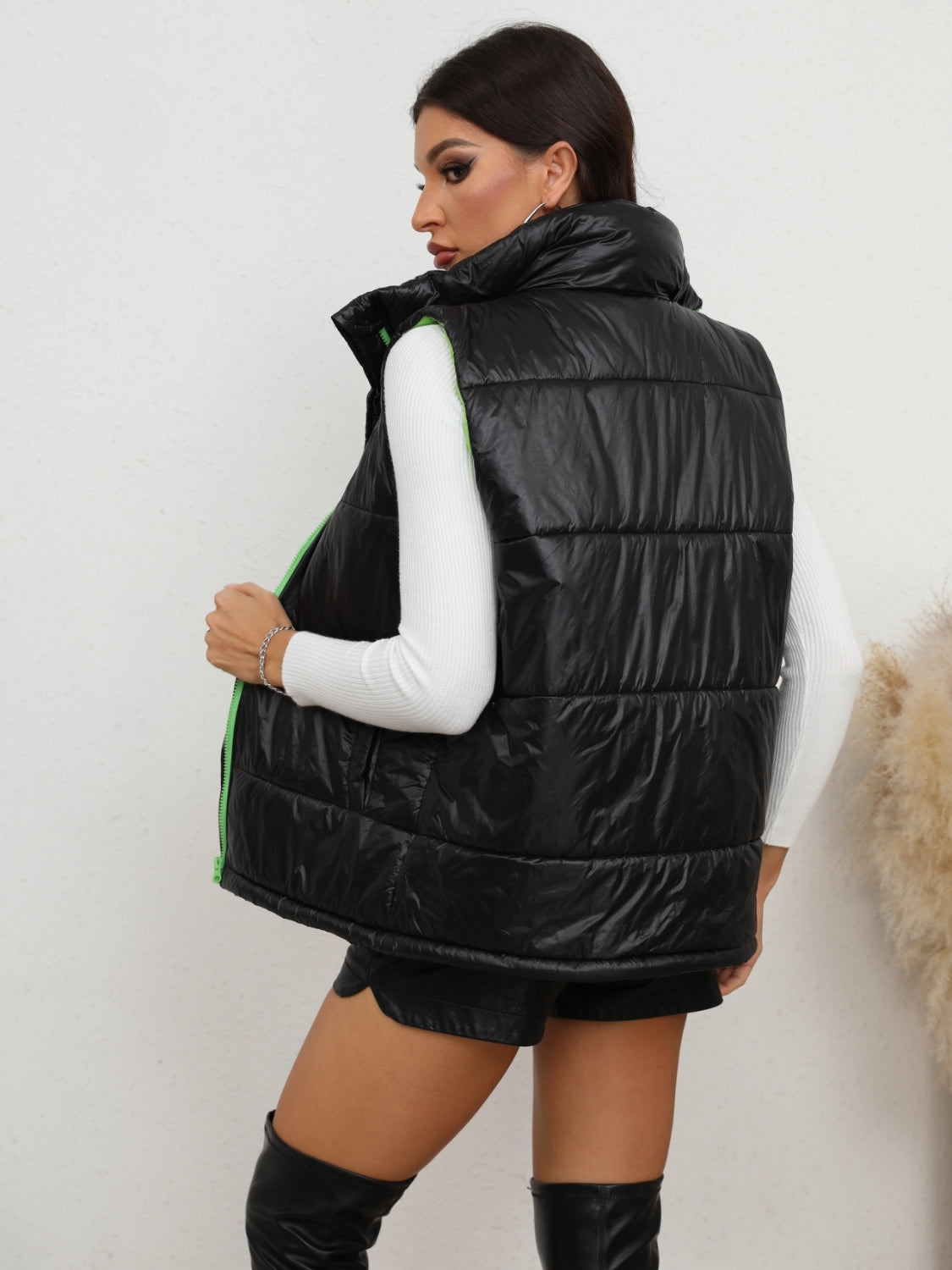 Black padded puffer vest with neon green zipper detail and high collar.