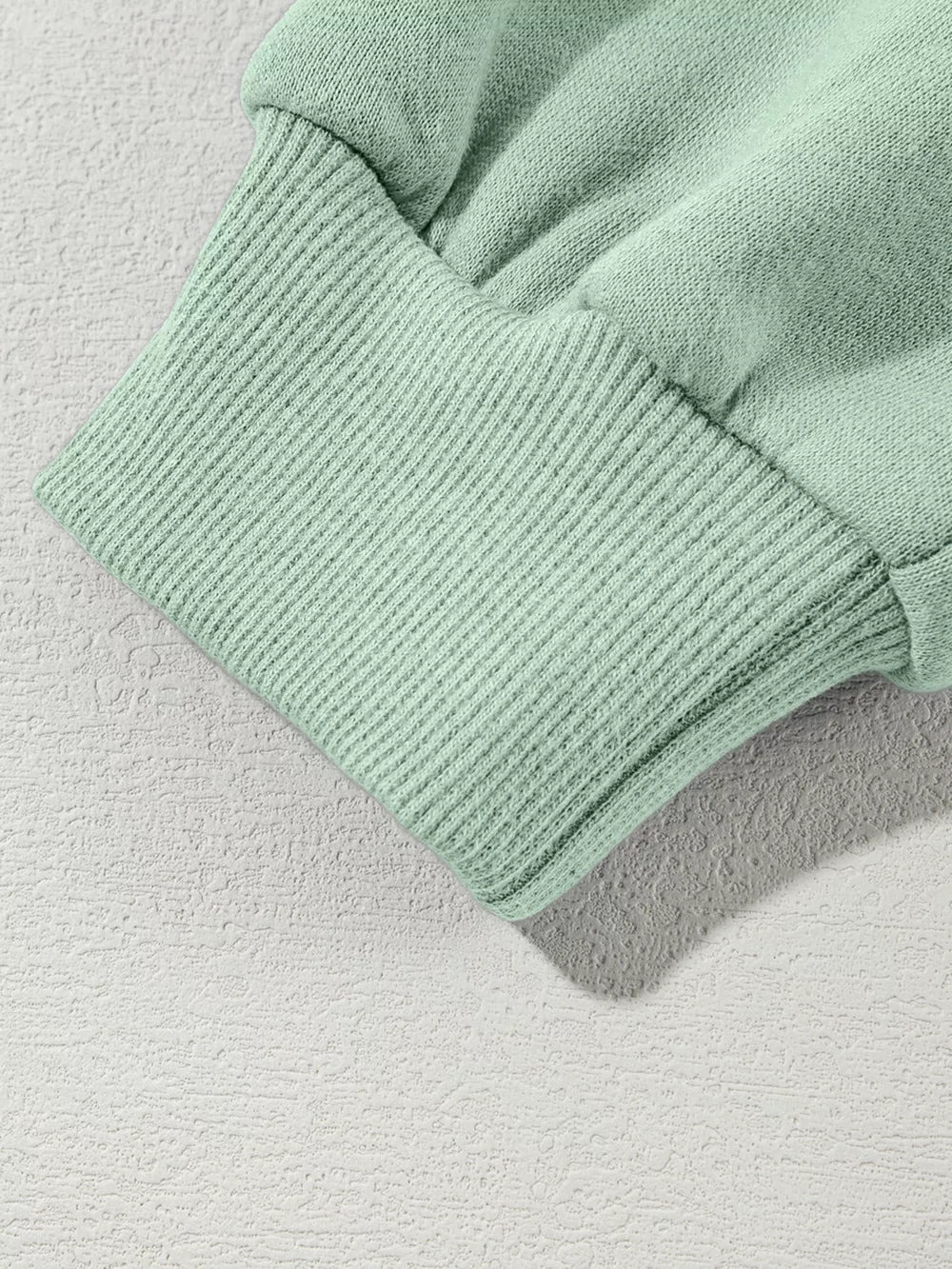 Sage green cotton joggers with ribbed cuffs and hem detail.