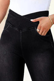 Black denim leggings with a crossover waistband and pocket detail.