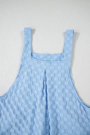 Light blue textured checkered jumpsuit with button straps and wide legs.
