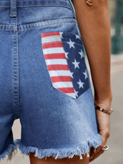 Distressed denim shorts with American flag pocket detail and frayed hem.