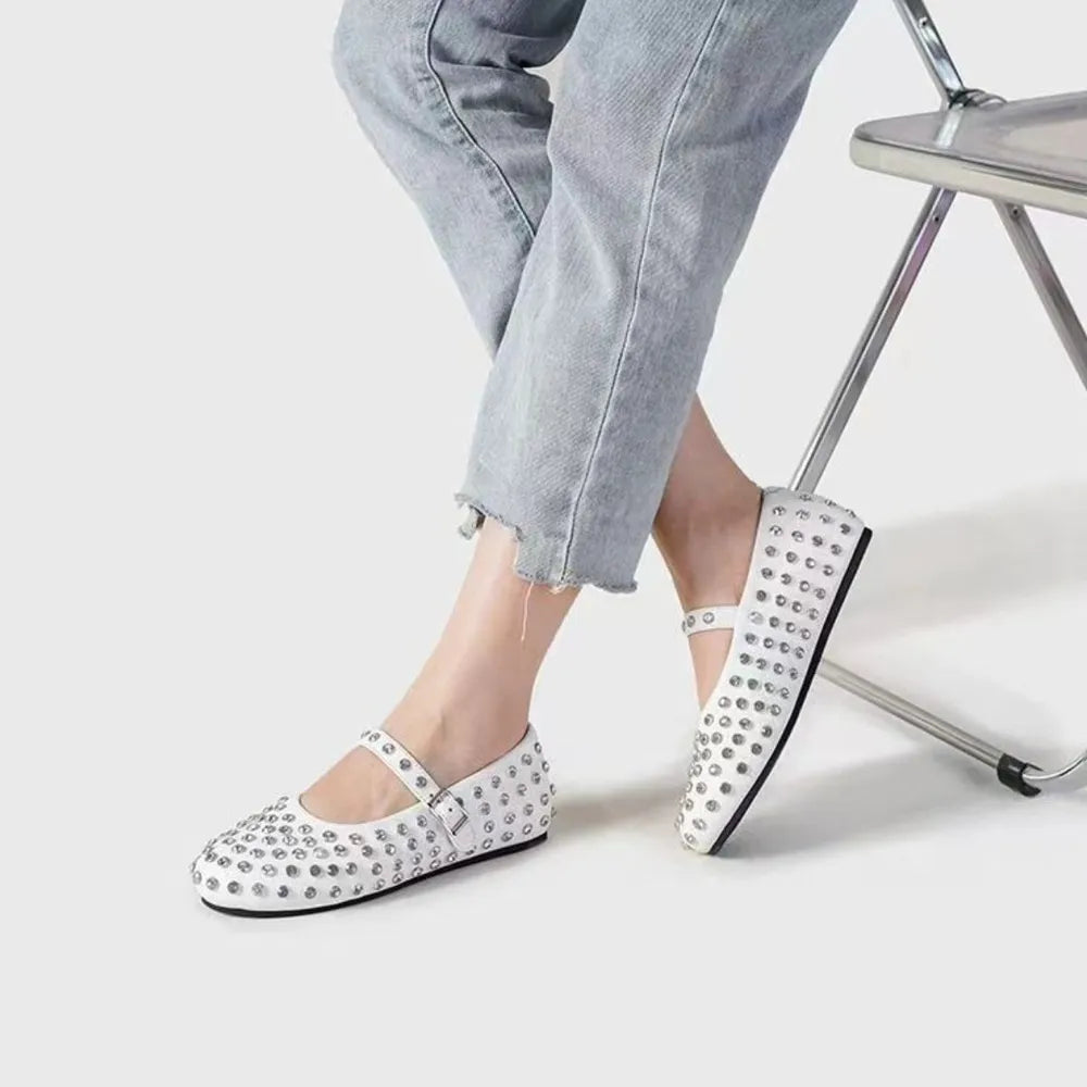 White studded Mary Jane flats with ankle strap, styled with cropped jeans.