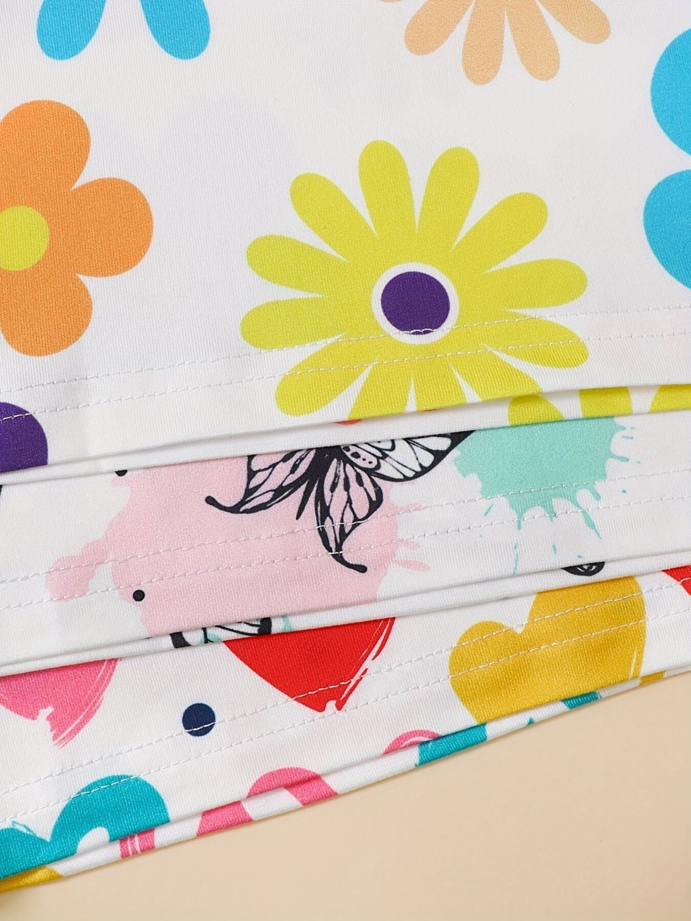 Baby set with white fabric, colorful flowers, butterflies, hearts, and paint splatters.