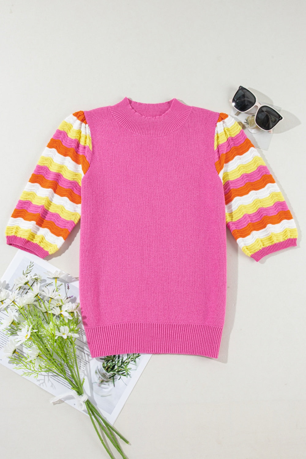 Fuchsia pink knit sweater with colorful striped puff sleeves and mock neck.