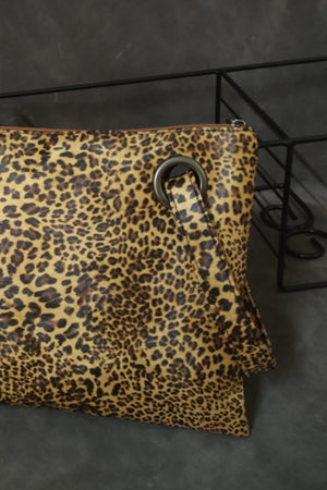 Leopard print clutch bag with a zip top and metal grommet detail.