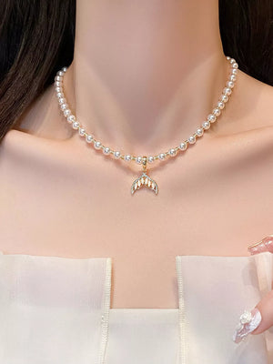 Pearl choker necklace with a gold mermaid tail pendant adorned with crystals.