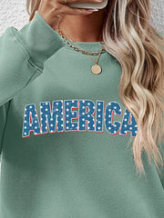 Sage green crewneck sweatshirt with distressed blue stars and white lettering spelling AMERICA