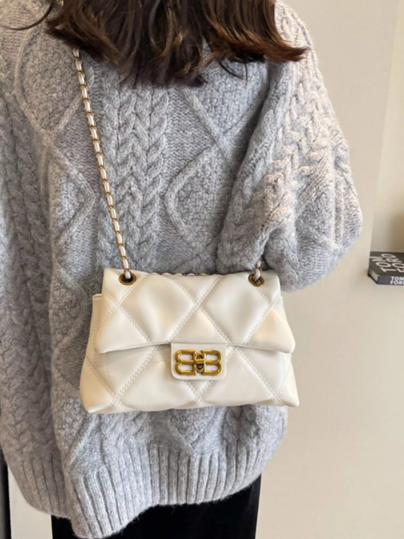 White quilted flap chain shoulder bag with gold hardware and a classic clasp.