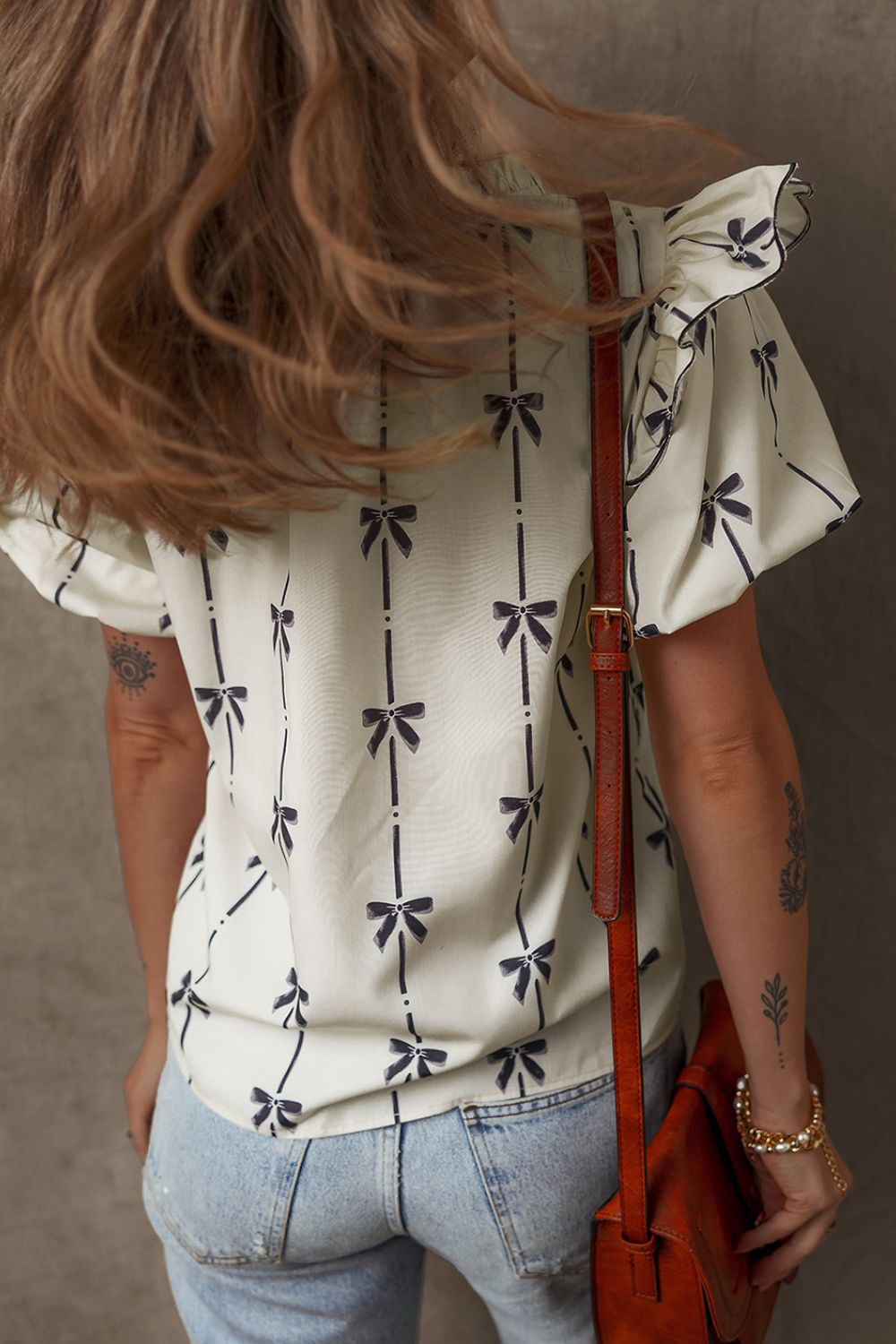 Ivory blouse with bow print, ruffled short sleeves, and a casual fit.