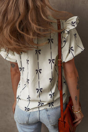 Ivory blouse with bow print, ruffled short sleeves, and a casual fit.