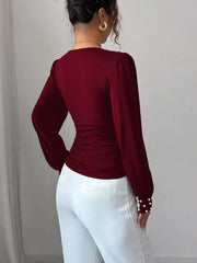 Burgundy ruched V-neck blouse with pearl embellished cuffs and puff sleeves.