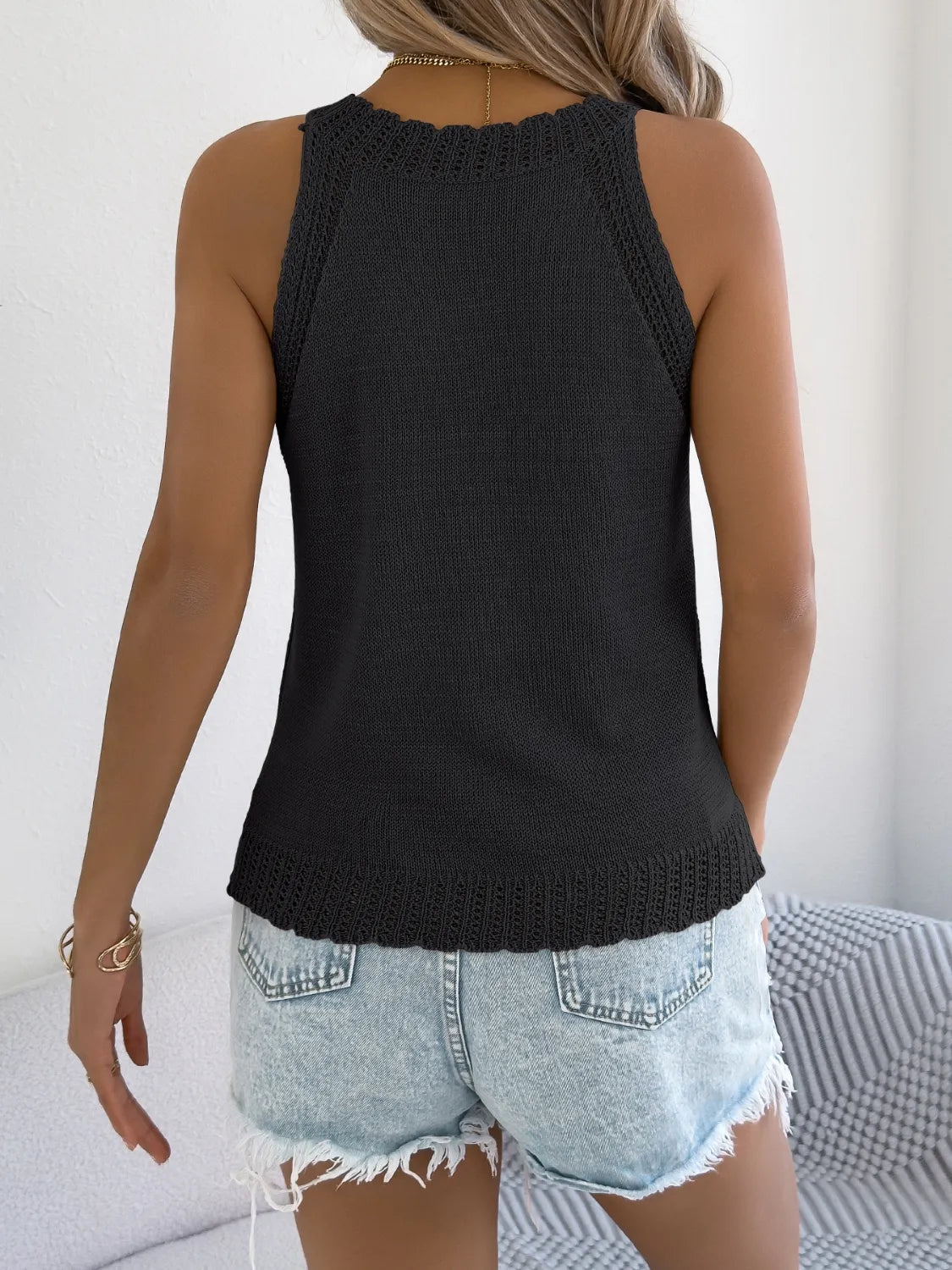 Black knit sleeveless top with scalloped neckline and hem detail