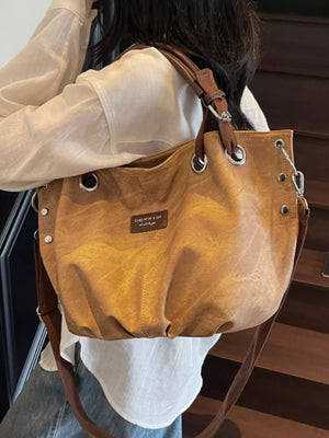 Slouchy crossbody bag in tan with adjustable strap and metal grommets