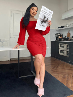 Red ruched bodycon dress with sheer long sleeves and a square neckline.