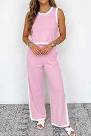 Chic colorblock two-piece set in blush pink with white trim, featuring a sleeveless crop top and wide-leg pants.