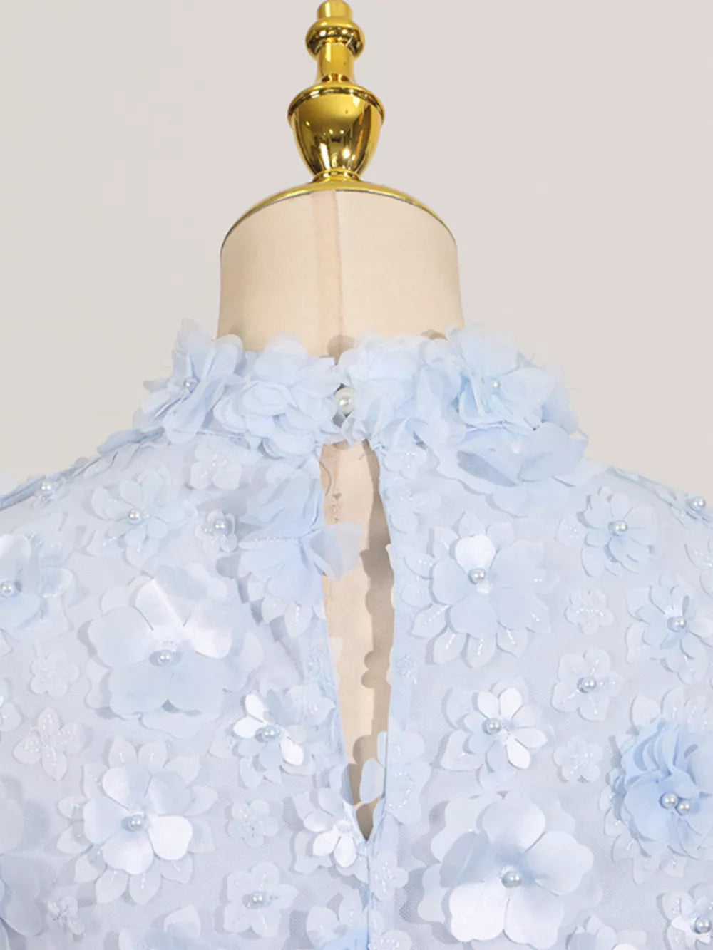 Blue mini dress with floral appliques and pearl accents on a high neckline.