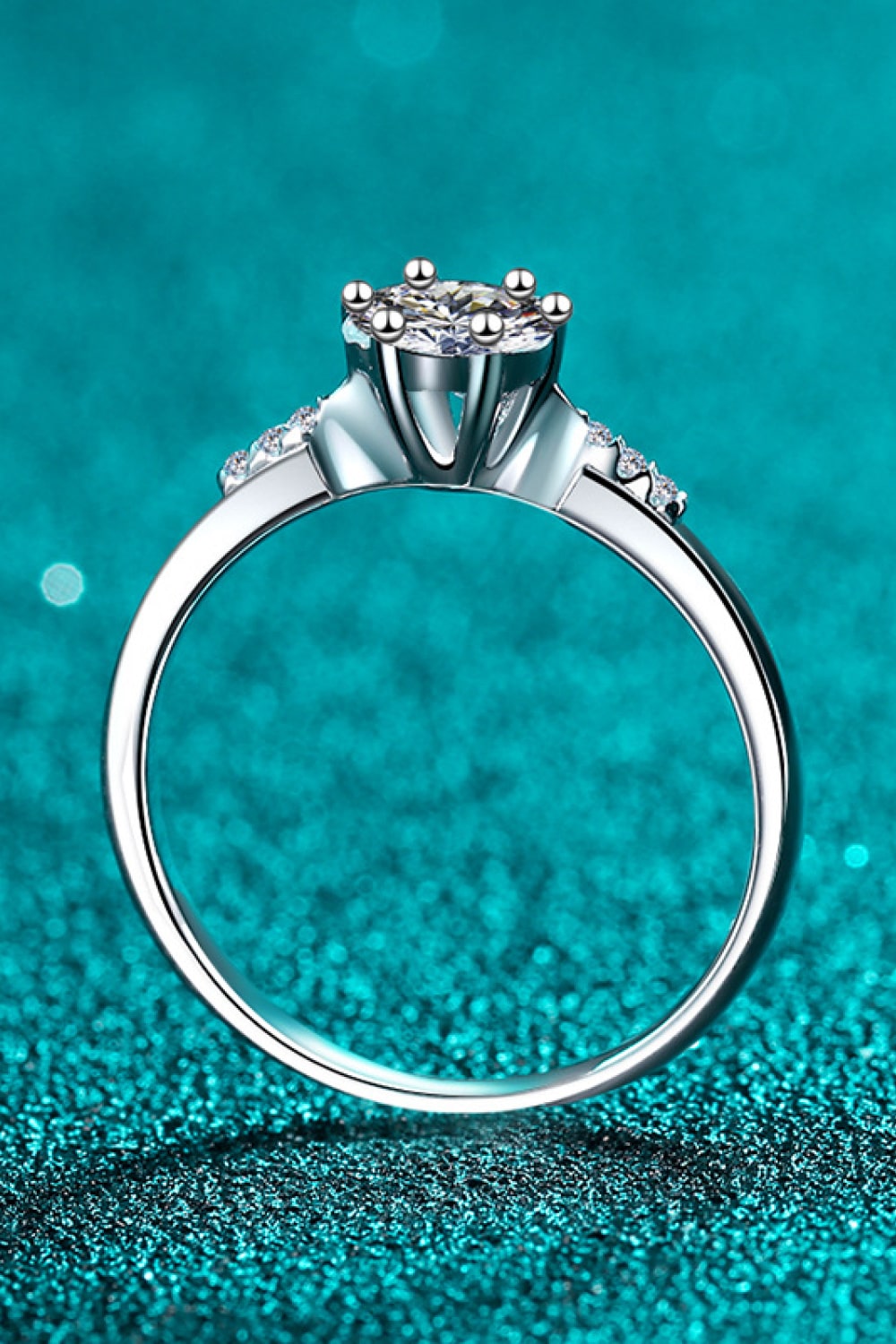 Silver moissanite engagement ring with floral cluster setting and accent stones.
