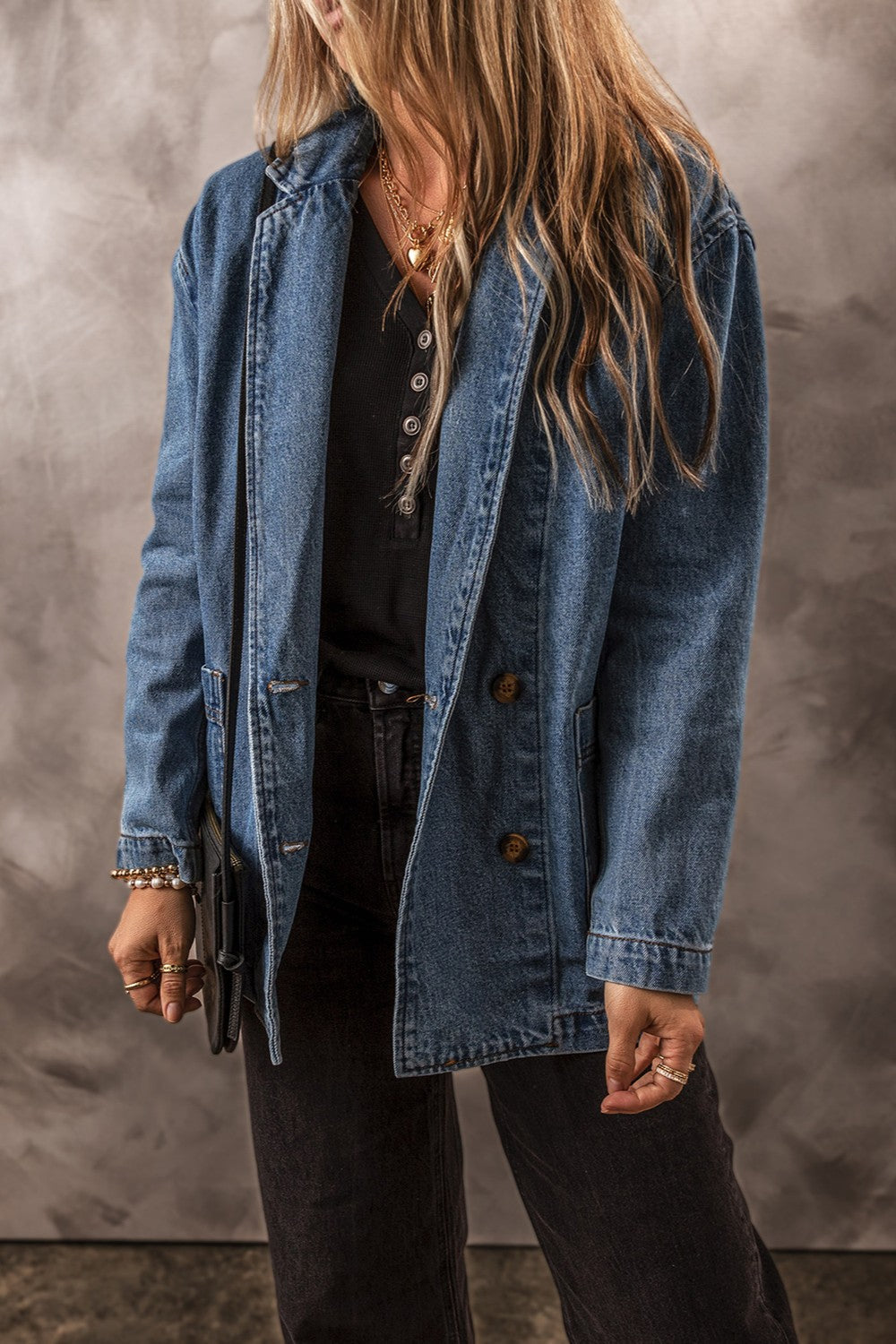 Medium wash denim double-breasted blazer with button closure and notched lapels.