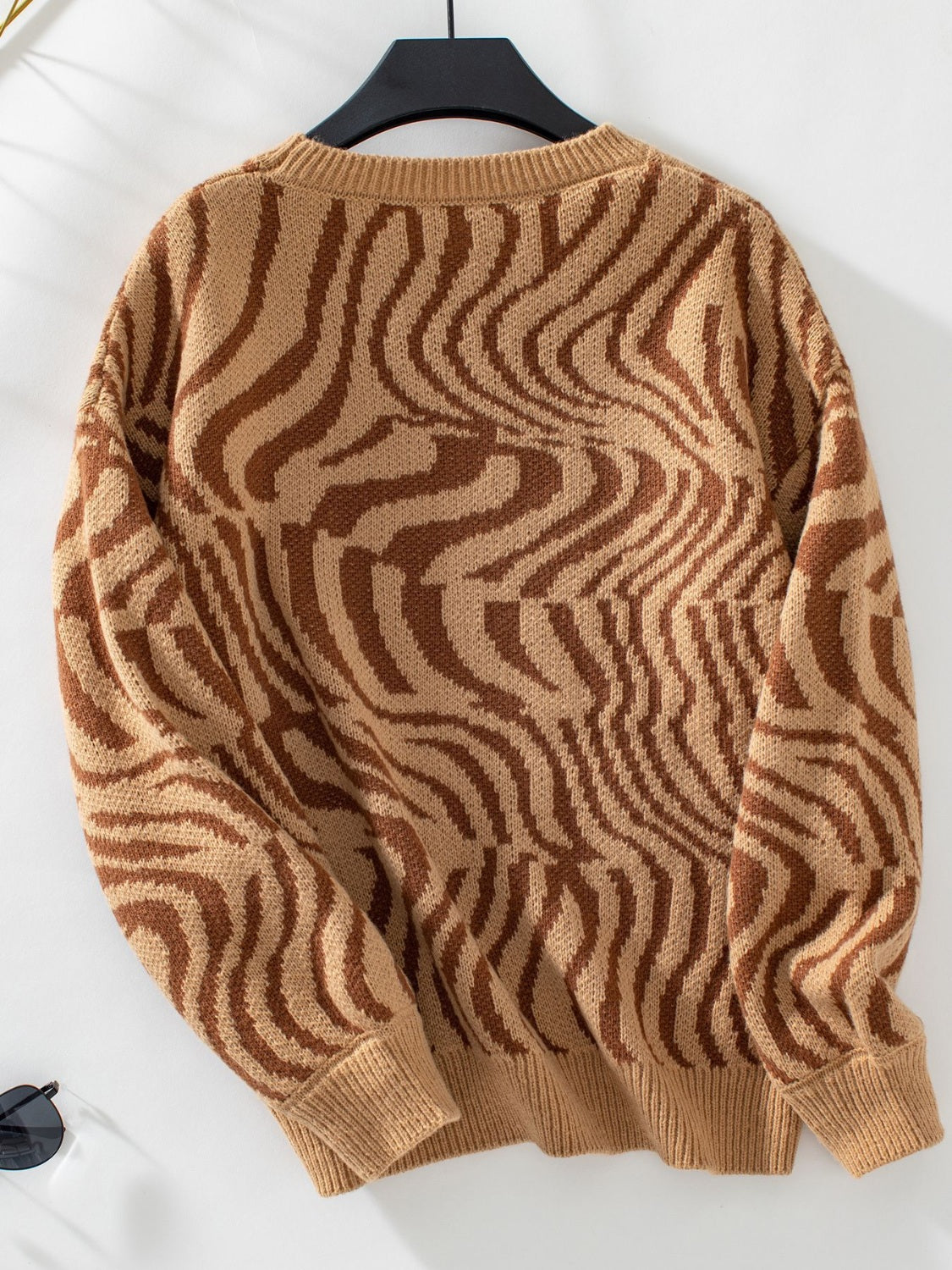 Camel wavy knit crewneck sweater with brown abstract pattern.