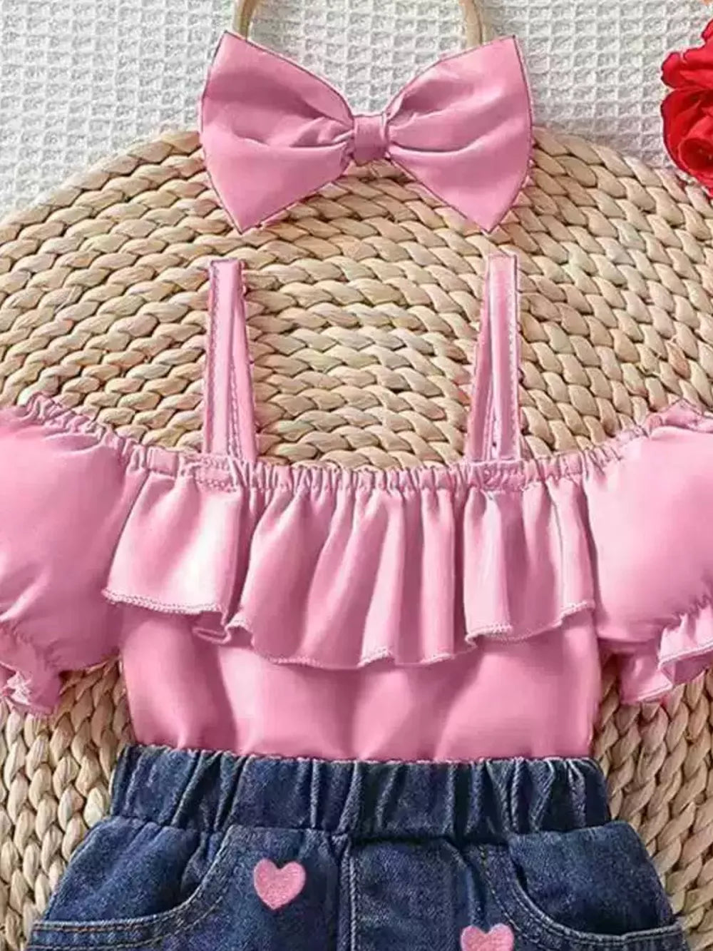 Pink ruffled off-shoulder baby top with denim shorts featuring heart details and a matching bow headband.