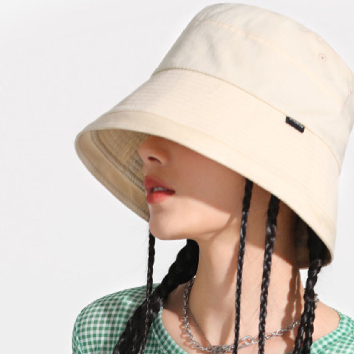 Beige cotton bucket hat with wide brim and black tag detail.
