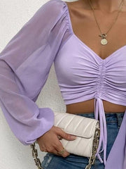 Lavender ruched bodice crop top with sheer puff sleeves and drawstring detail.