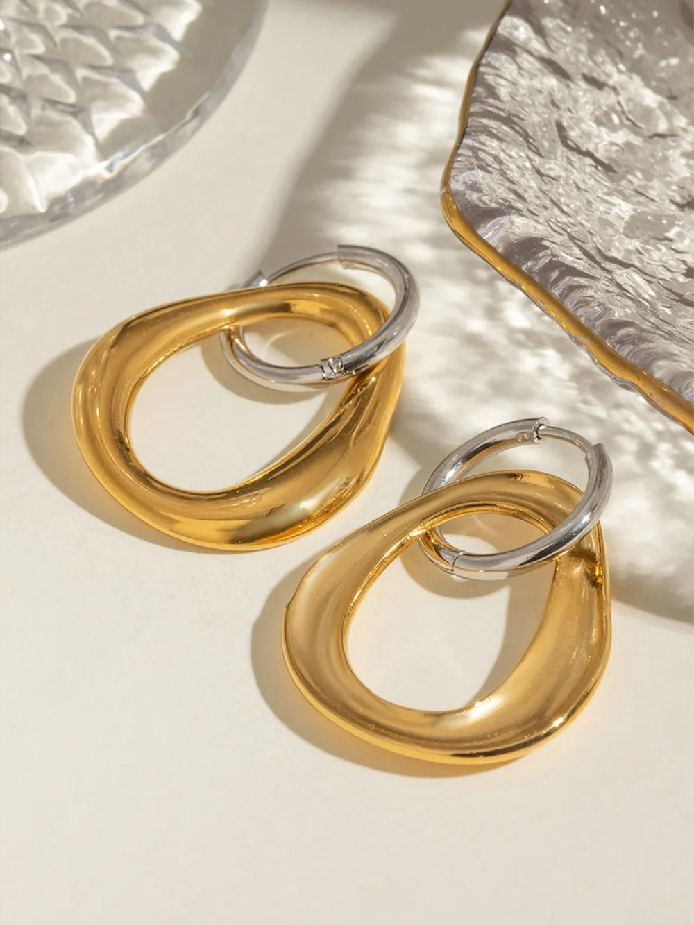 Two-tone sculptural asymmetric hoop earrings in gold and silver, 18K gold-plated.