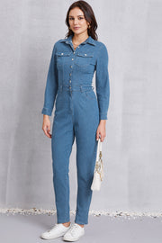 Denim utility jumpsuit in medium wash with defined waist, button front, and chest pockets.
