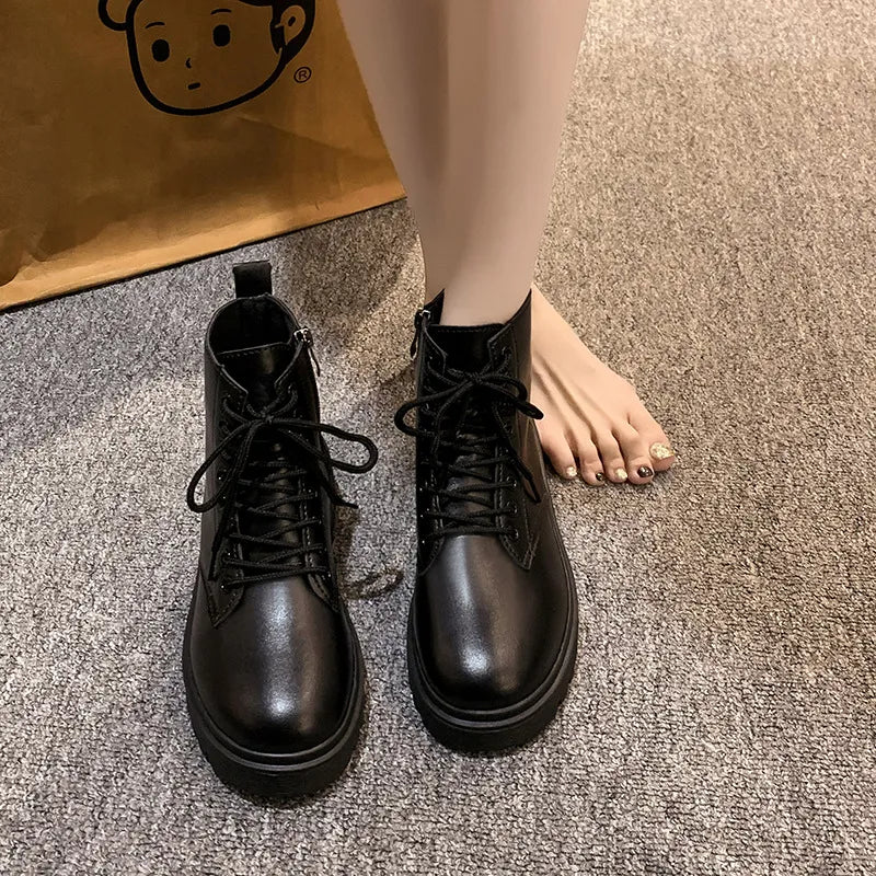 Black glossy leather combat booties with laces and side zip detail.