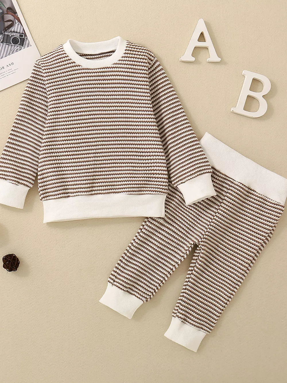 Baby knit set with brown and white stripes, long sleeves, crewneck, and matching pants.