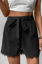 Black high-waisted shorts with tie-waist and lace hem detail.