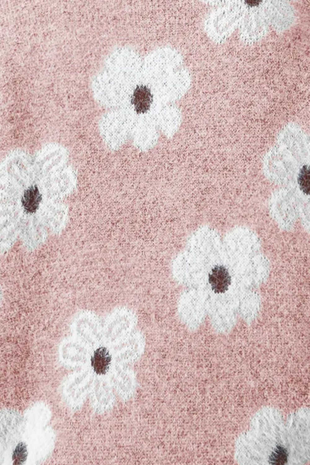 Blush pink acrylic sweater with white floral intarsia pattern and dark centers.