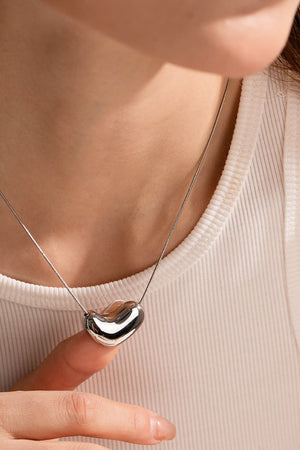 Silver bean-shaped sculptural pendant necklace on a snake chain.