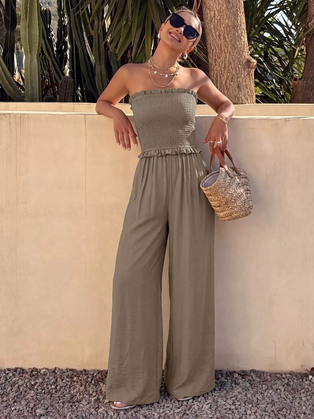 Smocked strapless olive green romper with frill detail and wide-leg pants.