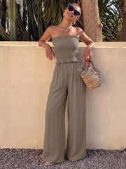 Smocked strapless olive green romper with frill detail and wide-leg pants.