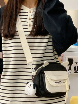 Black and white cat ear crossbody bag with adjustable strap and plush dog charm.