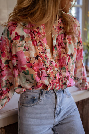 Pink floral print blouse with ruffle yoke and button front.