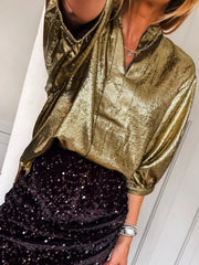 Gold crinkled blouse with 3/4 sleeves and notched V-neck, styled with a sequined skirt.