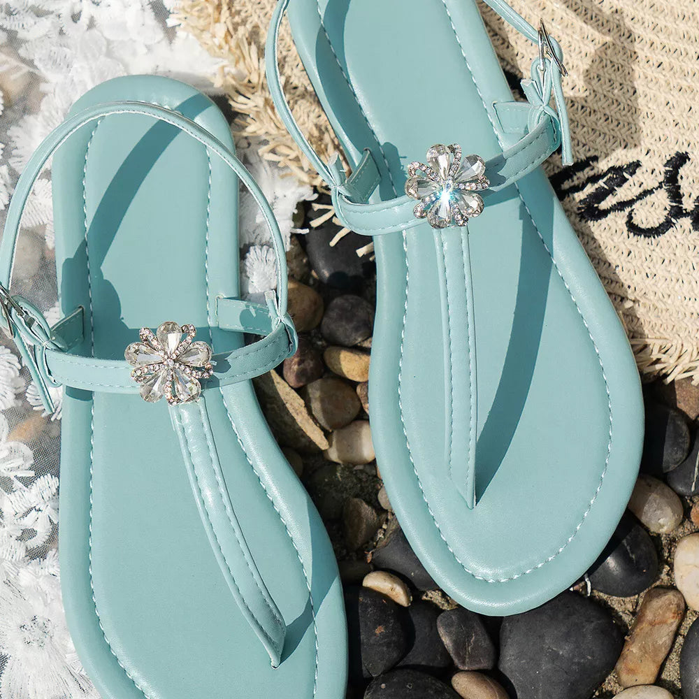 Lake blue flat sandals with floral gem embellishments and ankle straps.