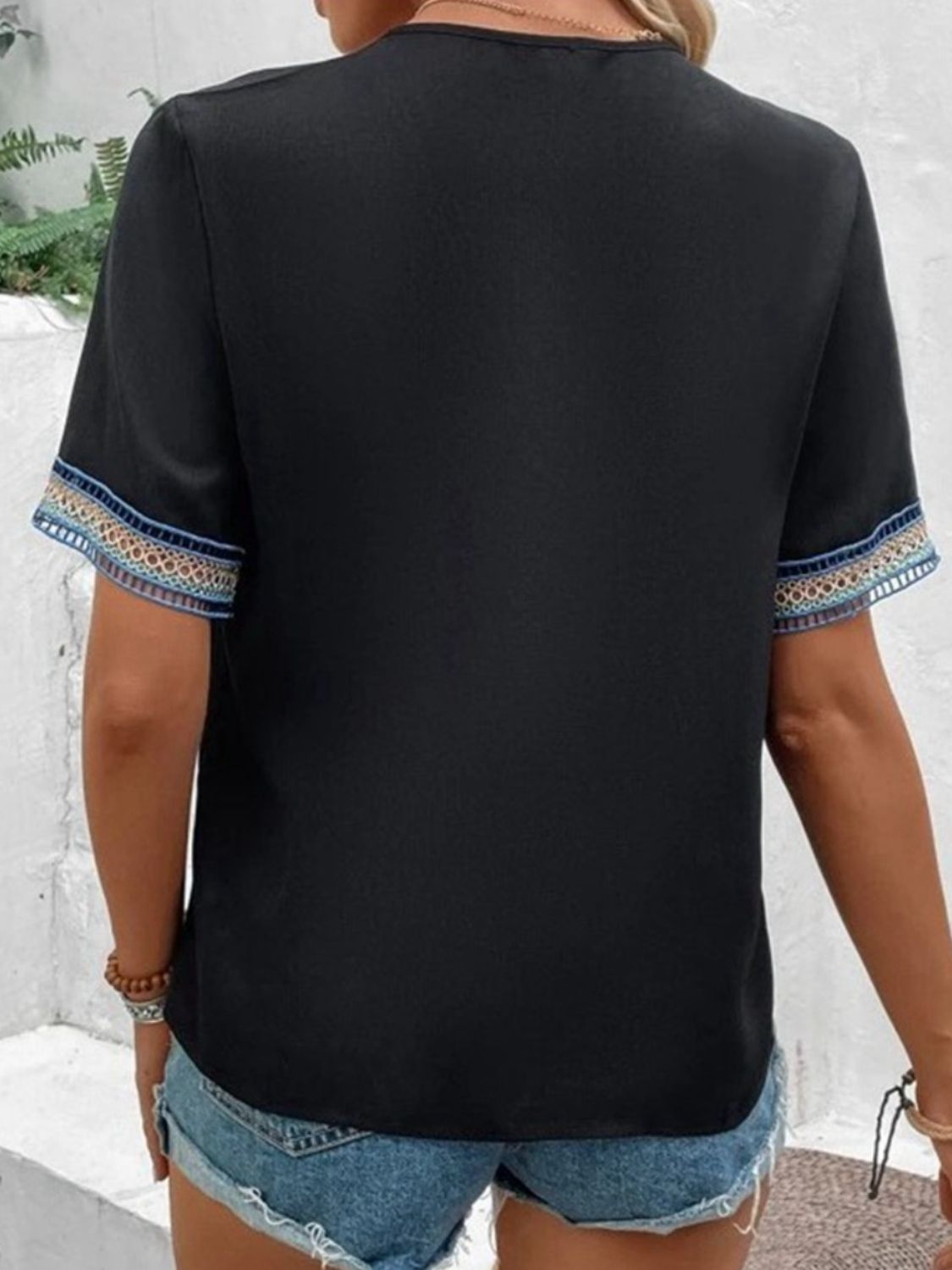 Black V-neck top with embroidered trim on sleeves