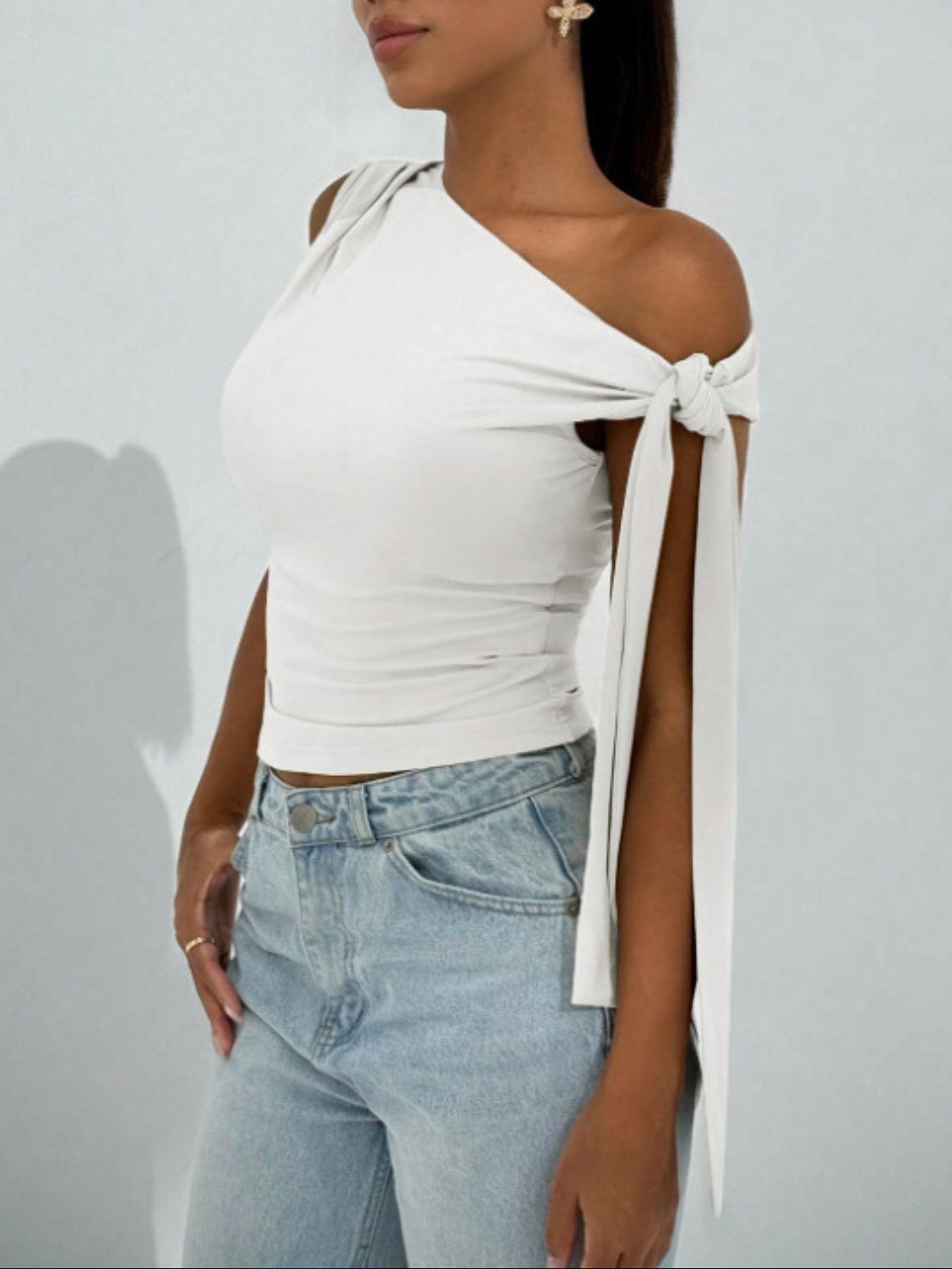 White asymmetrical tie detail cropped blouse with one shoulder and tie sleeves.
