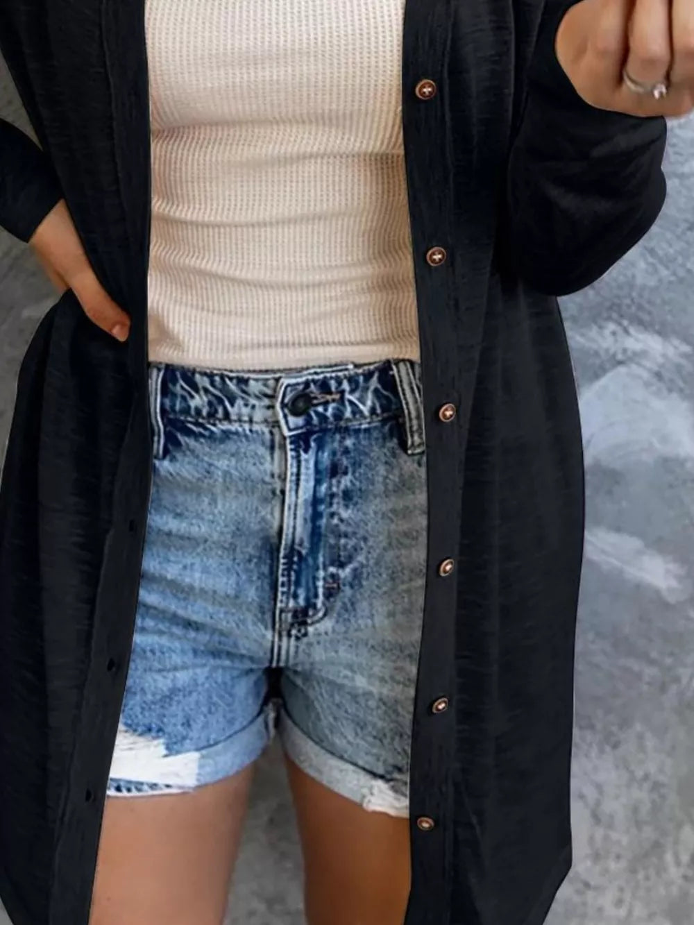 Black button-down cotton cardigan worn open over a cream waffle knit tank and denim shorts.