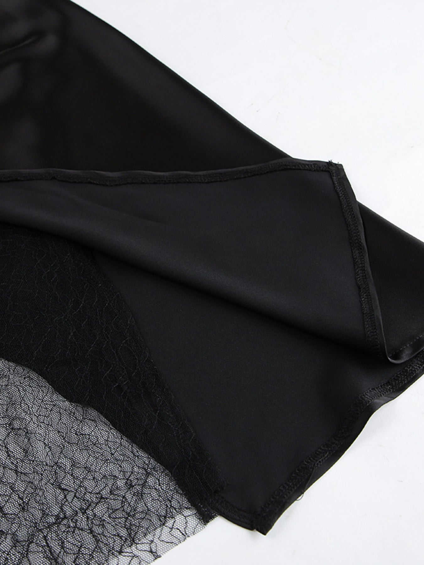 Black midi skirt with sheer lace panel detail and asymmetrical hem.