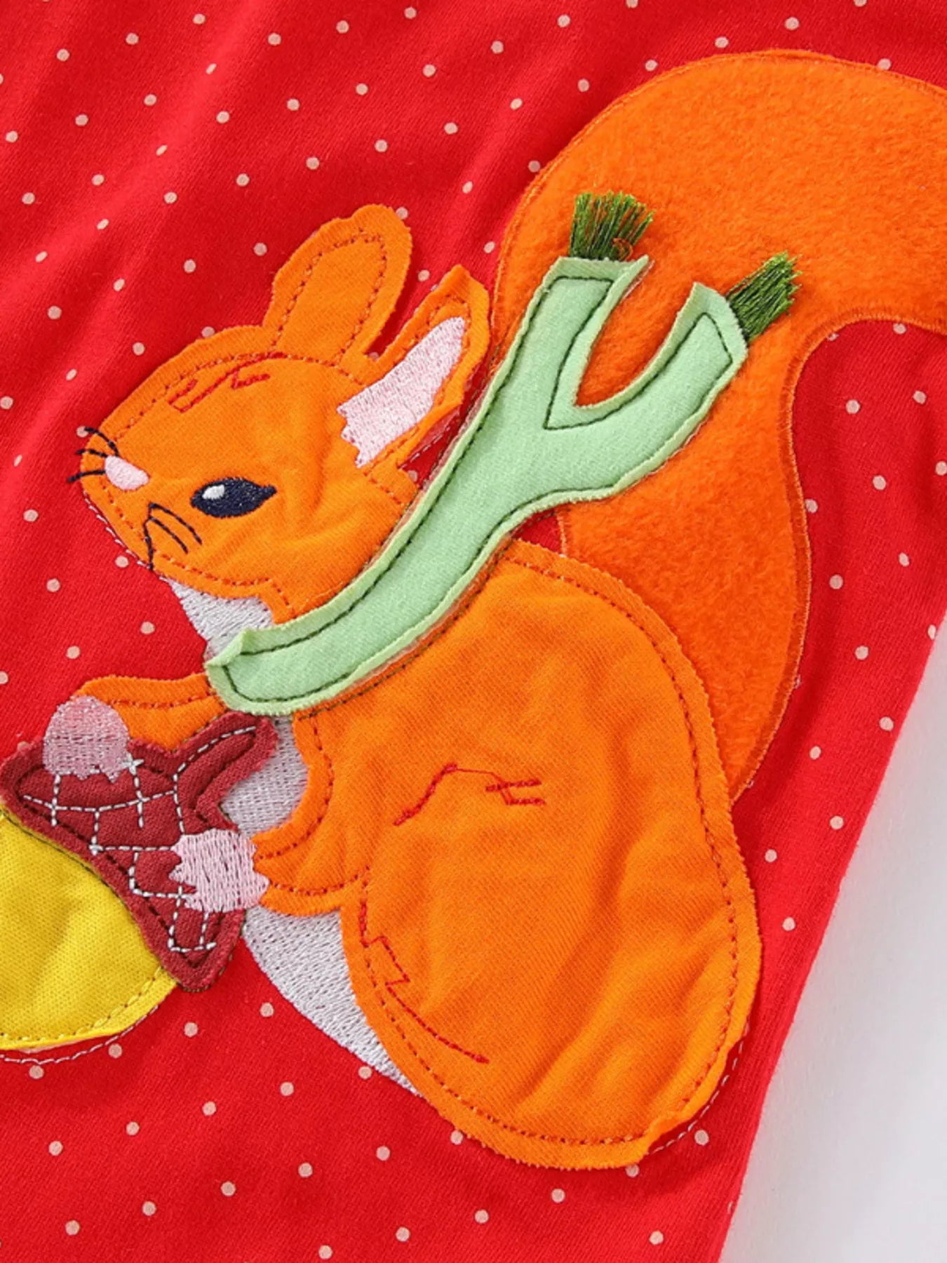 Red polka dot dress with a squirrel applique holding an acorn.