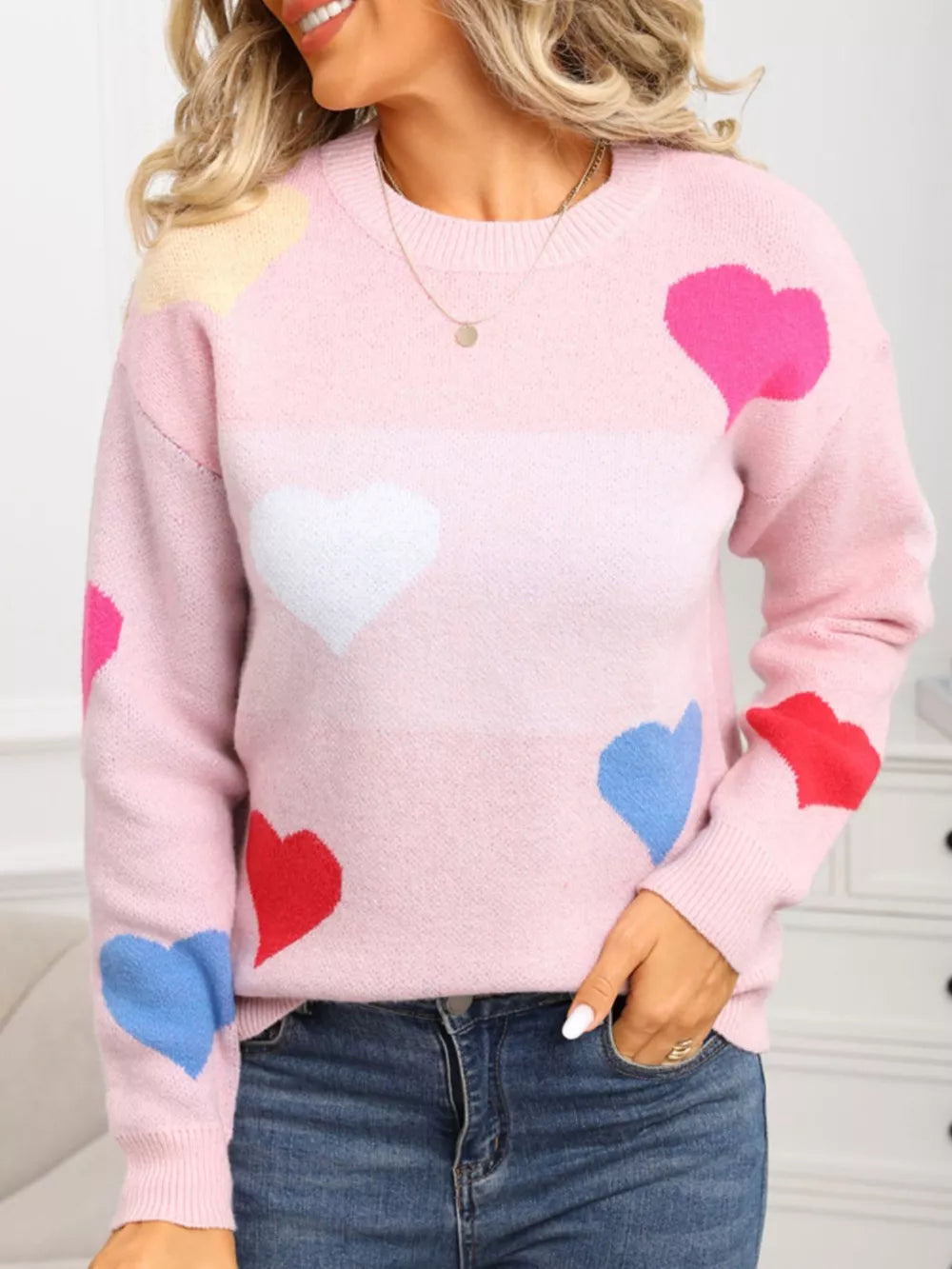 Pink acrylic knit sweater with multicolor hearts and round neck.