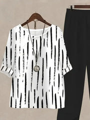 White half sleeve top with black vertical brushstroke print and black pants.