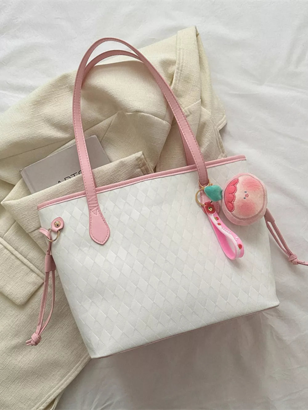 Textured diamond woven tote bag with pink trim and a fruit charm.