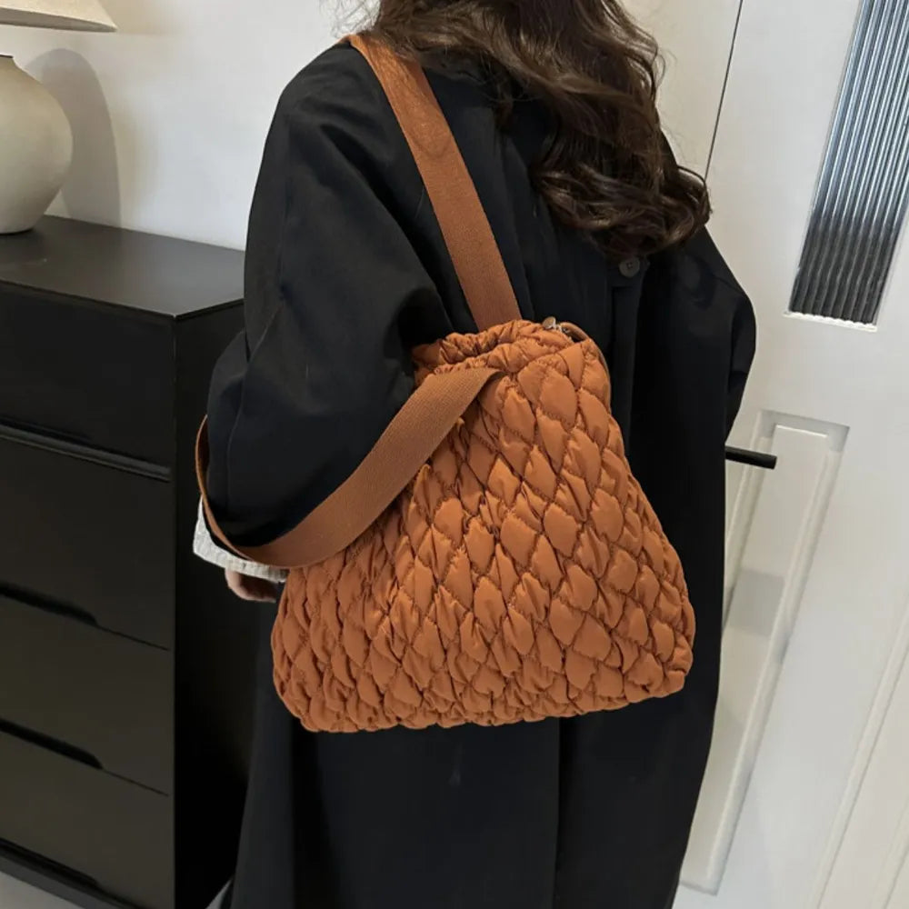 Terracotta quilted drawstring carryall bag with a casual crossbody strap.