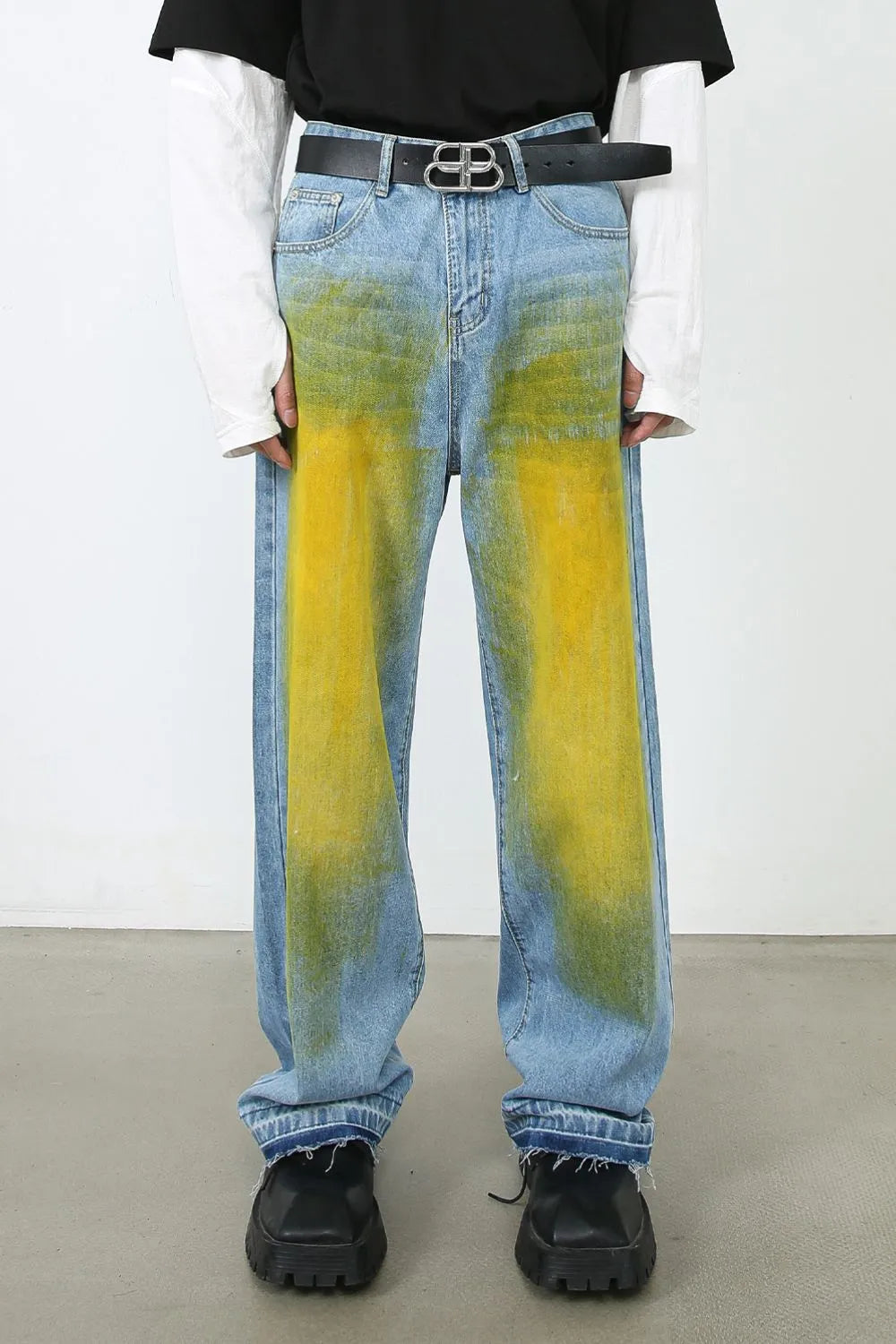 Oversized medium wash denim jeans with yellow and green spray paint effect.